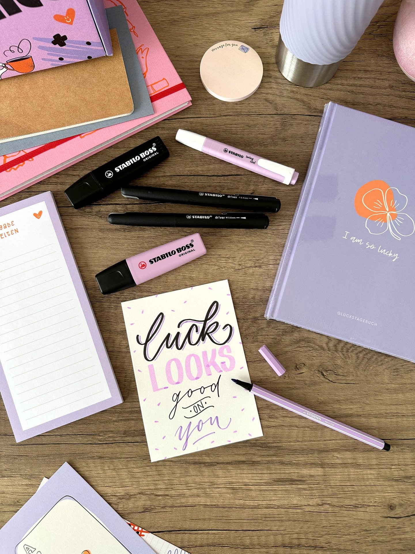 Purple stationery set on a wooden desk with Stabilo Boss highlighters and a hand-lettered card.