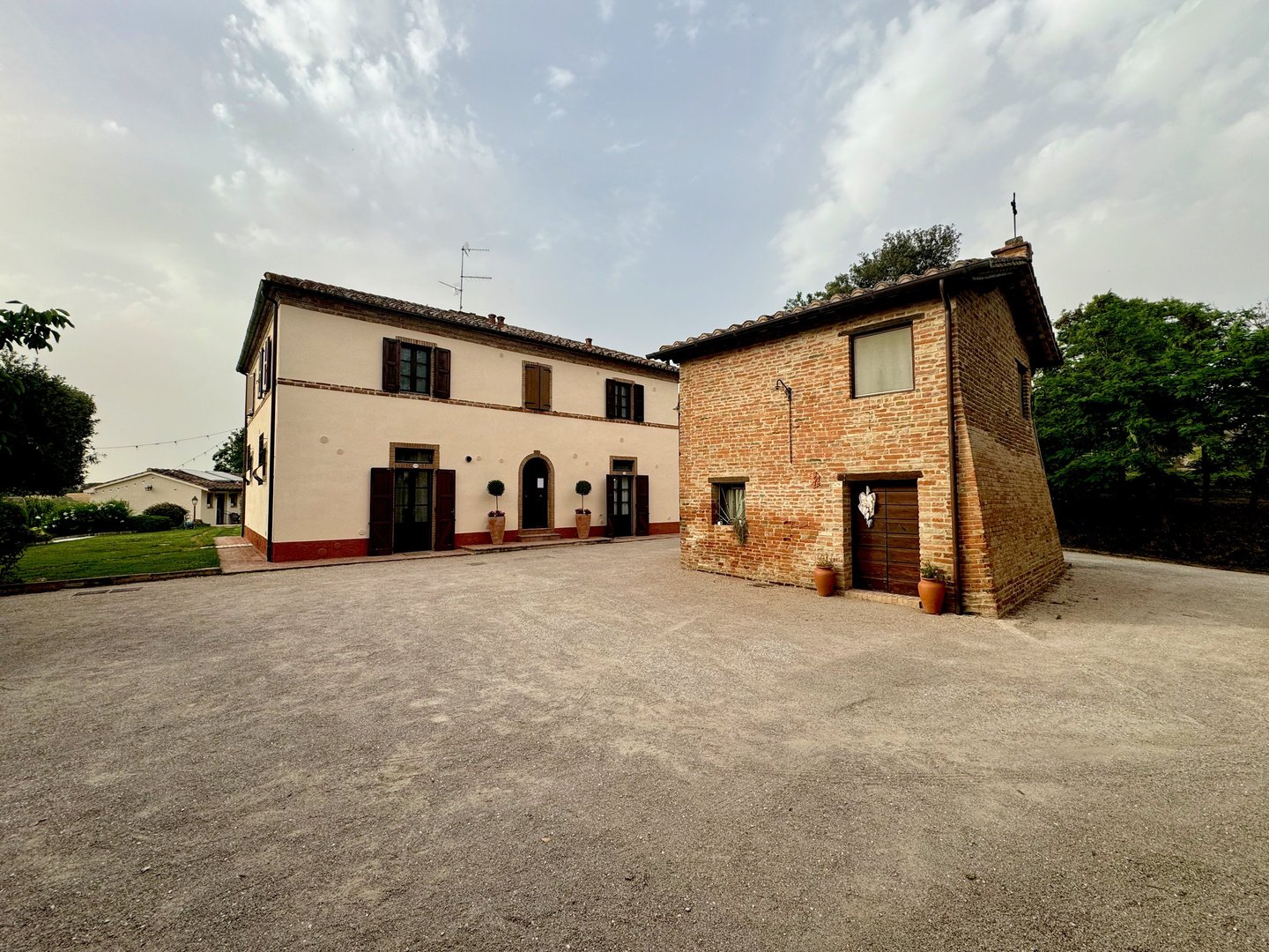 Rustic Italian stone villa and brick farmhouse on a gravel courtyard in Tuscany.