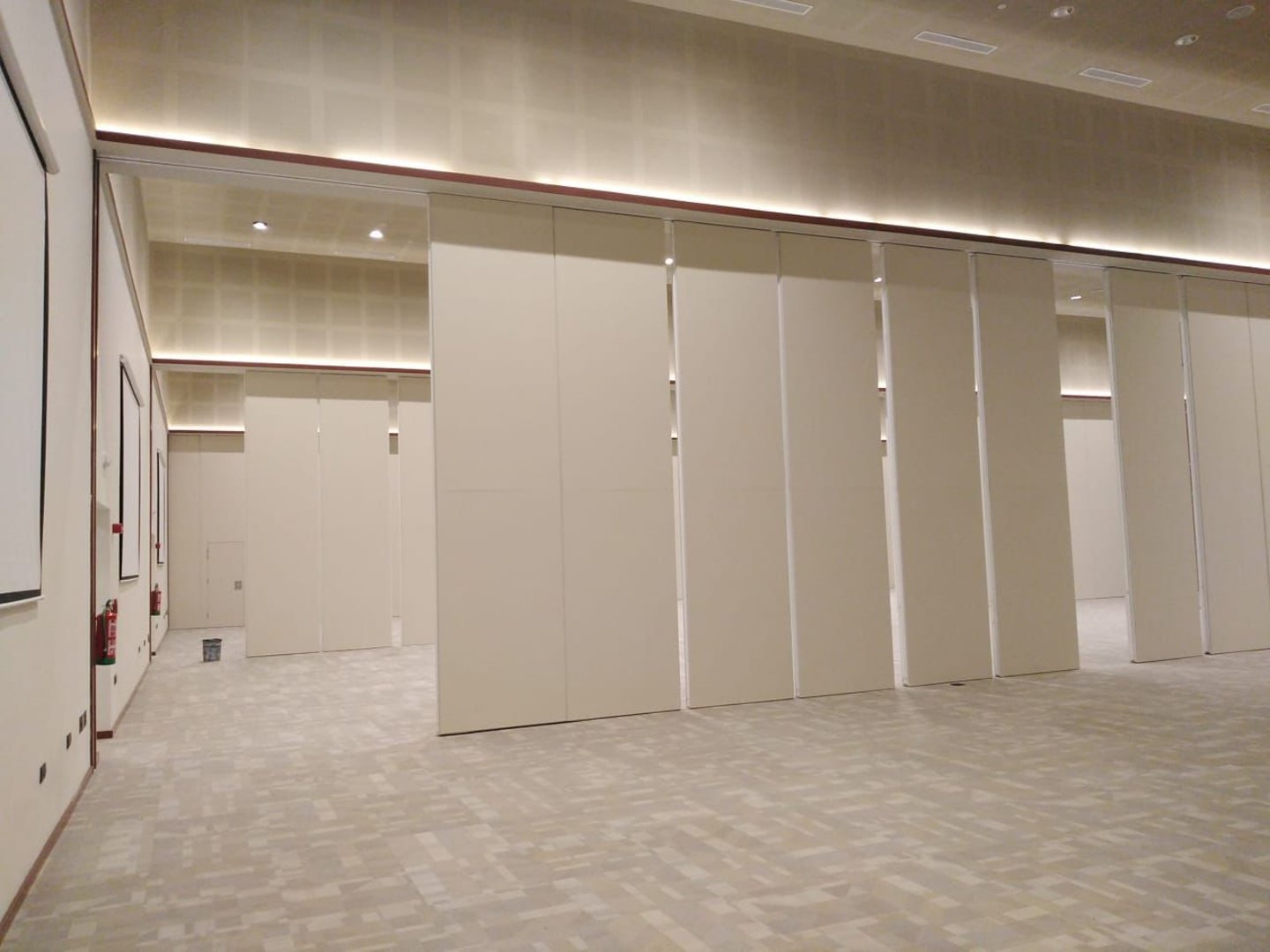 Movable acoustic wall panels installed in a modern conference hall for flexible room division.