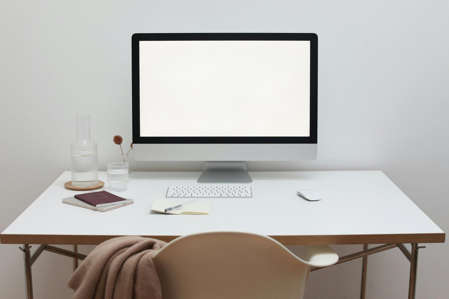 Minimalist home office desk featuring a silver computer monitor with a blank white screen.