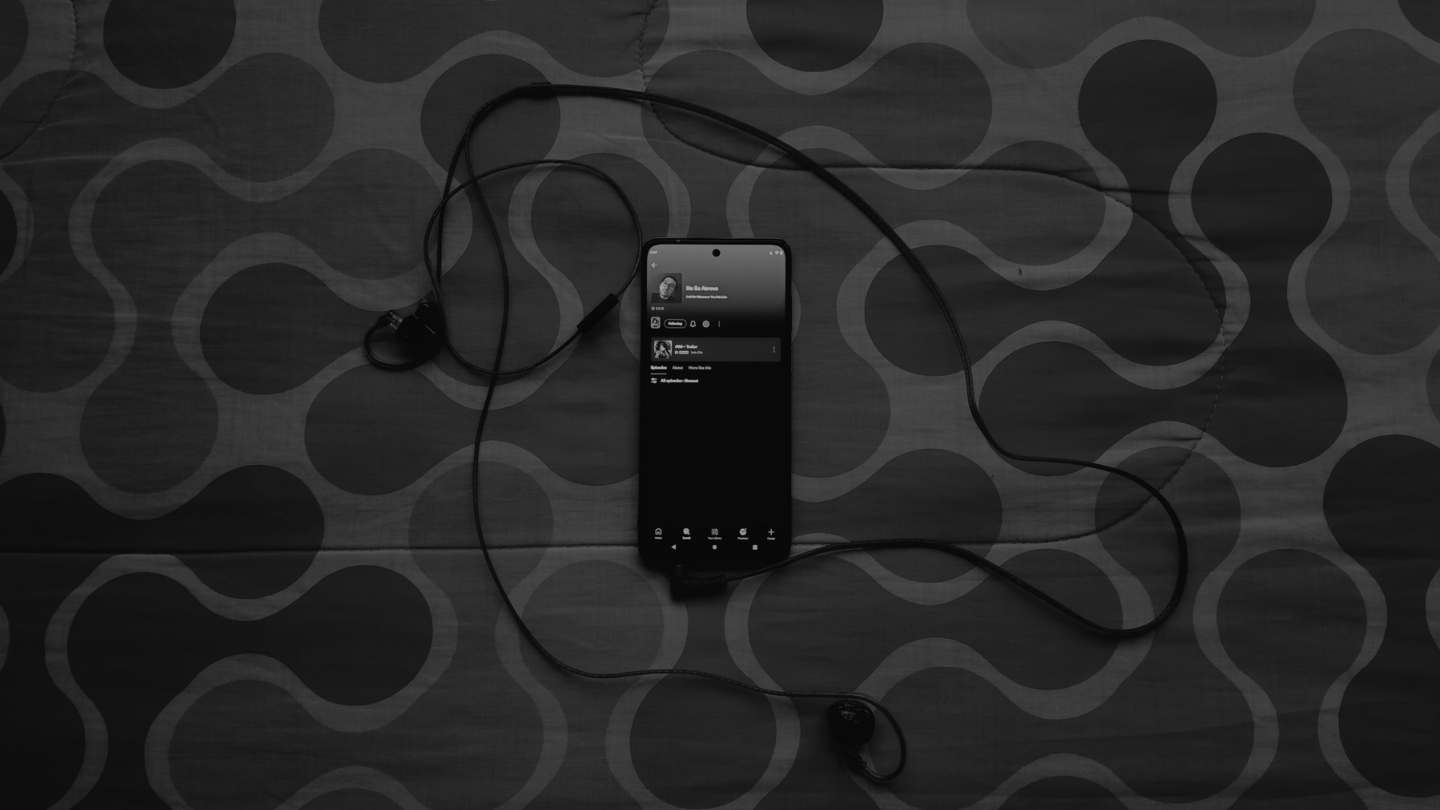 Teléfono con auriculares sobre tela gris mostrando el pódcast No Se Atreva en una escena íntima