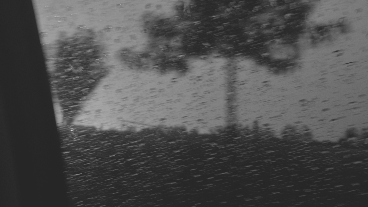 Paisaje difuso y gotas de lluvia sobre el vidrio de un auto.