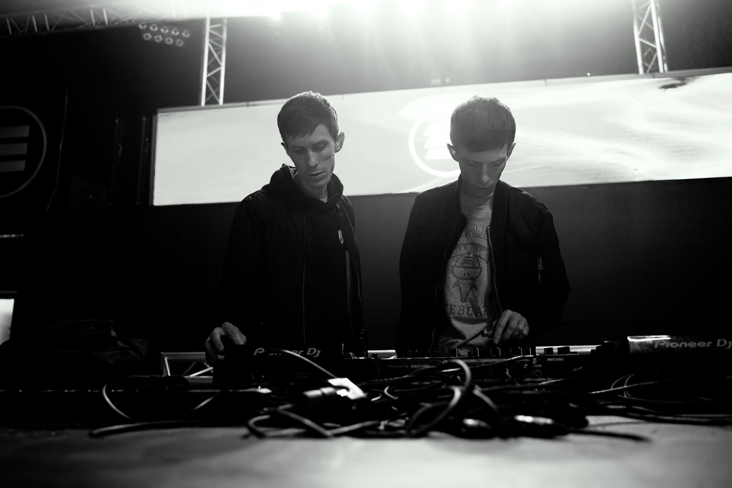 Twins brothers standing in front of a stage with a large screen