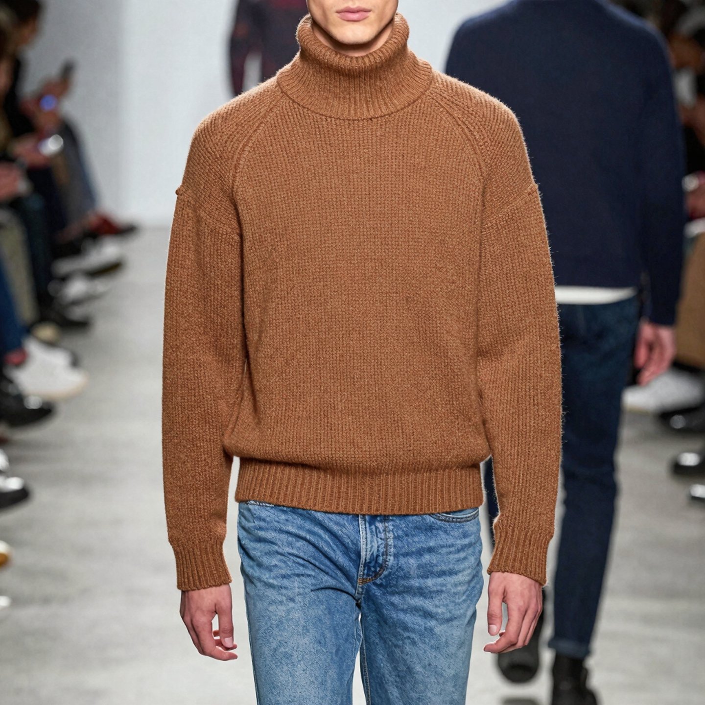 A sleek editorial shot of a male model wearing a minimalist black against a soft grey urban backdrop.