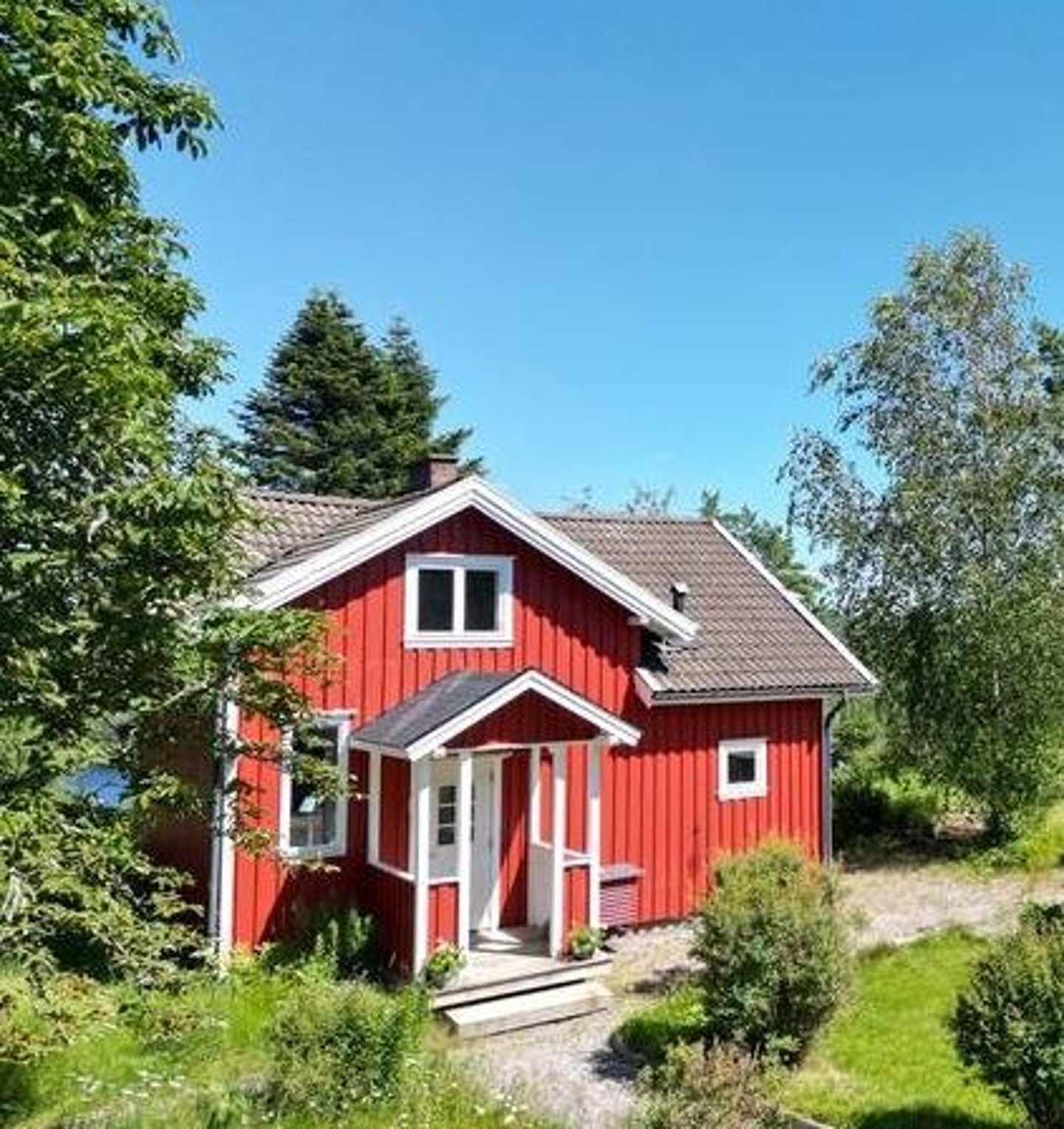 Maison peinte en rouge de falun sur bois de façade au soleil dans la végétation 
