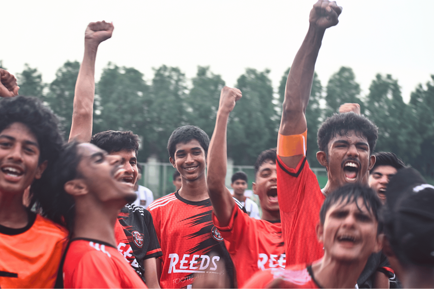 Reeds FC football players in red jerseys cheering with raised fists after a victory.