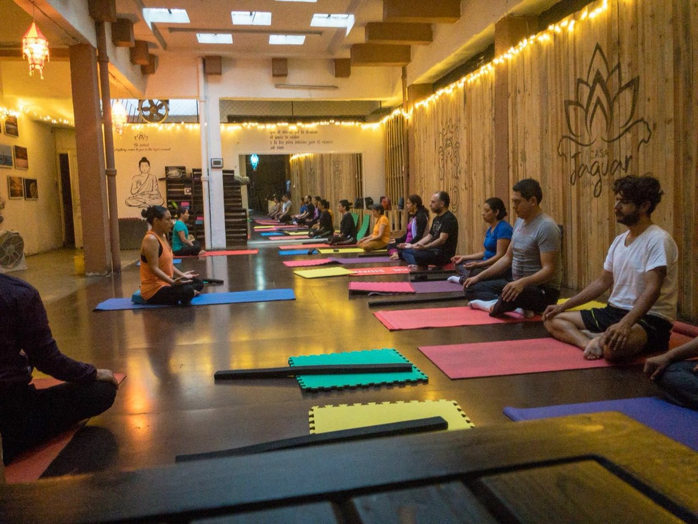 Grupo de personas practicando meditación en estudio de yoga cálido y bien iluminado en Ajna Oaxaca.