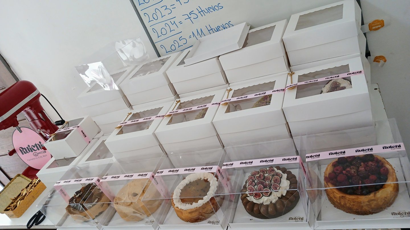 Assorted gourmet cakes and cheesecakes in white pastry boxes for bakery delivery or takeout.