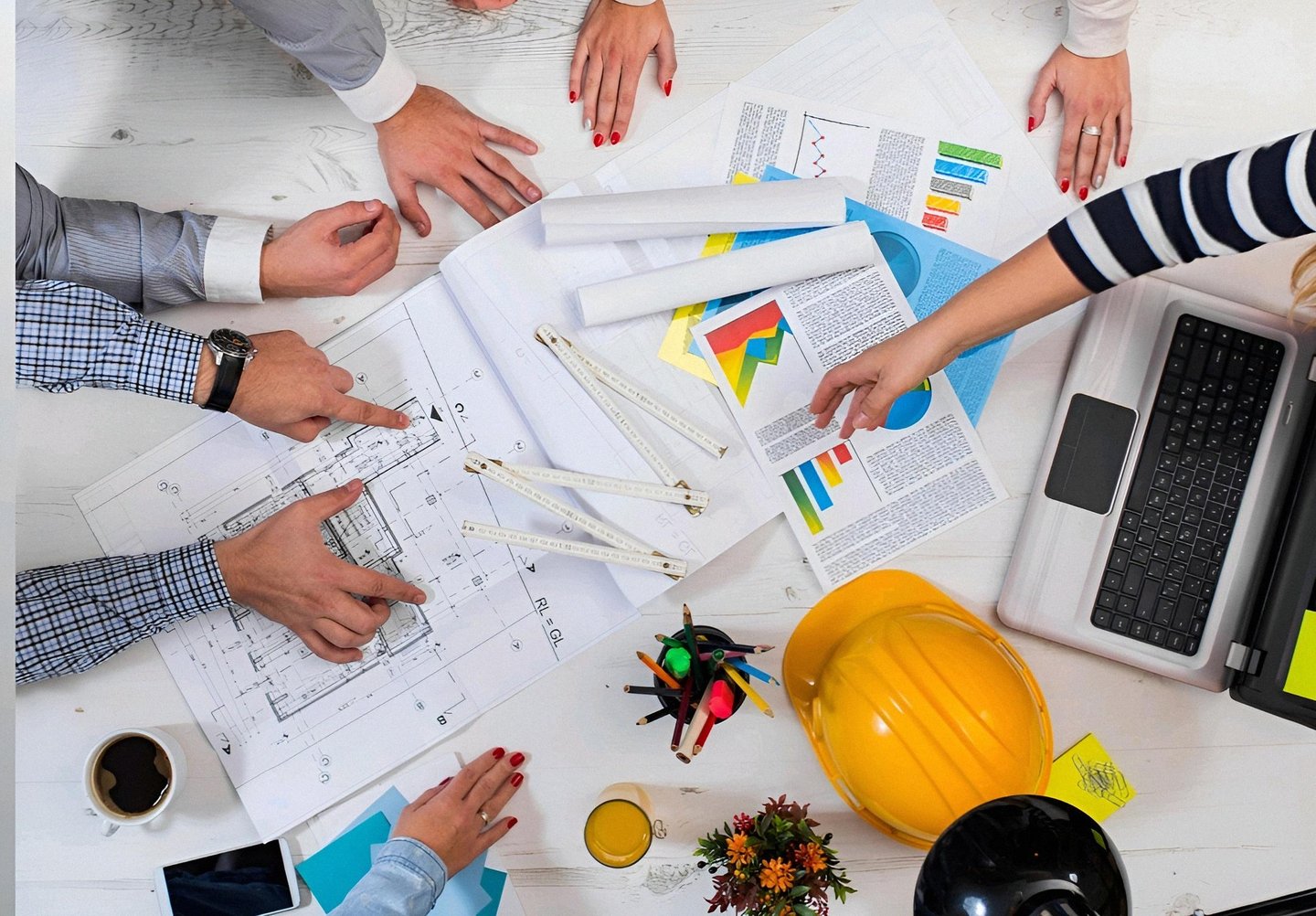 Team of architects and engineers reviewing construction blueprints and data charts during a project meeting.