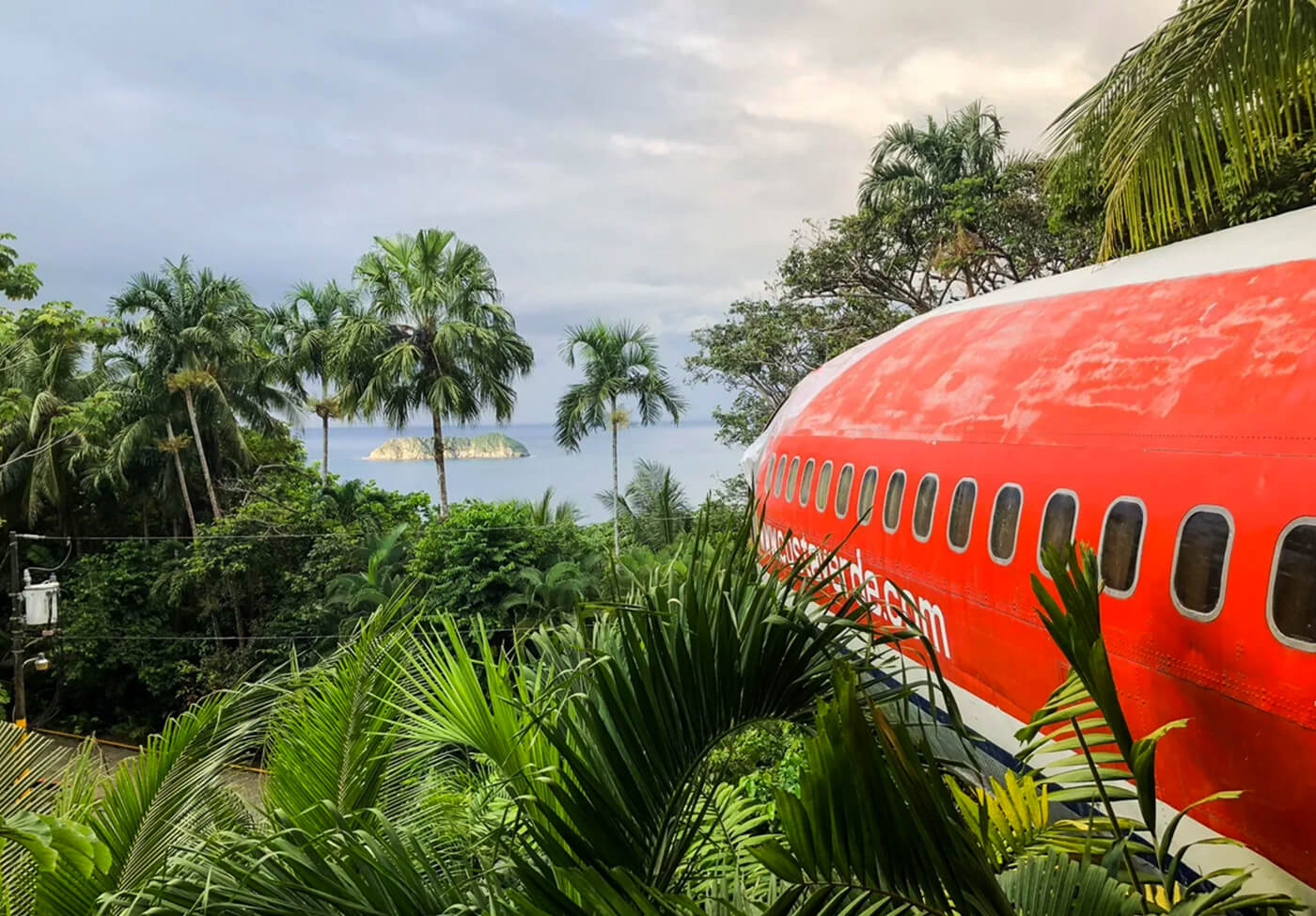 A vintage red airplane converted into a hotel suite nestled in a lush Costa Rican jungle overlooking the ocean.