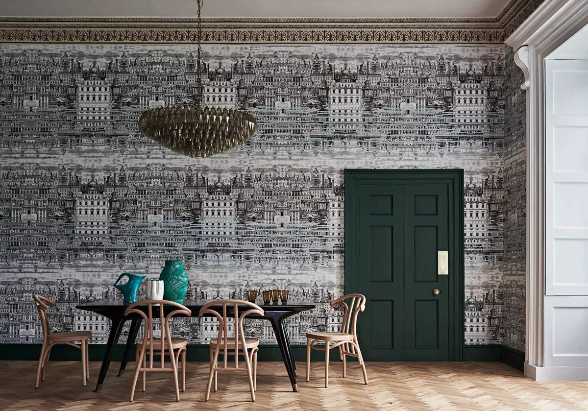 Modern dining room featuring architectural black and white wallpaper, a dark green door, and wooden chairs.