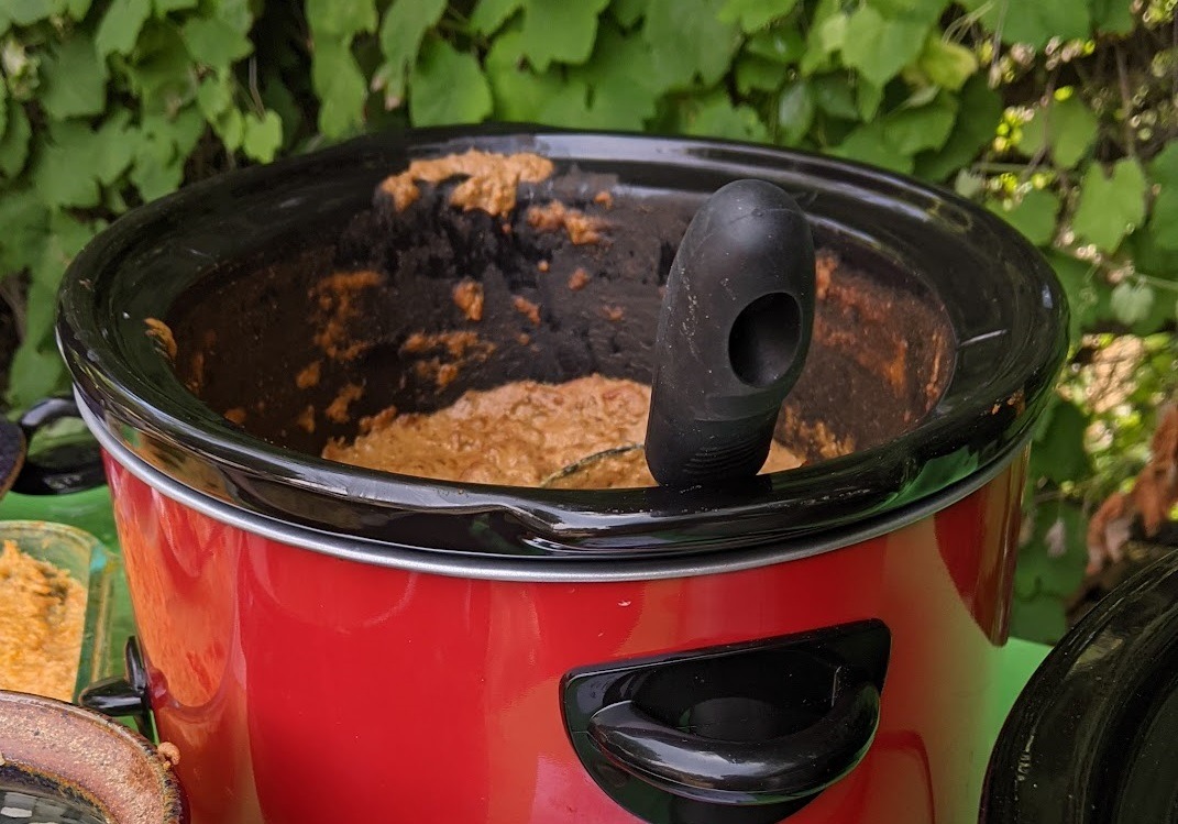 red and black crock pot with butter chicken inside