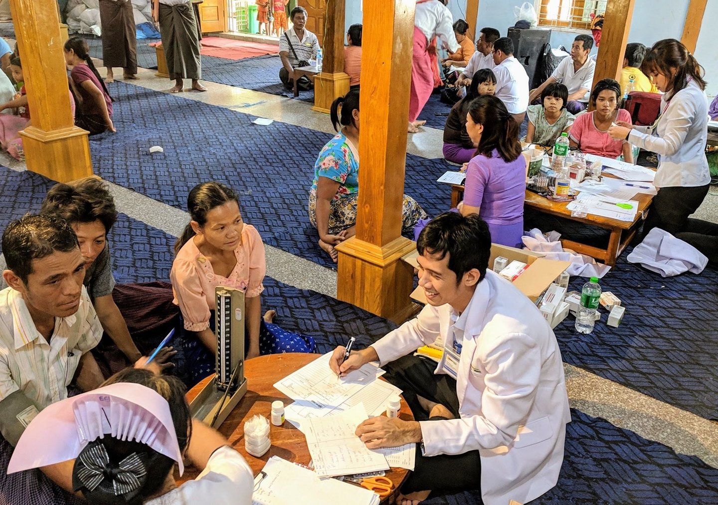 Doctor Zaw surrounded by patients sitting and counselling them in a smile
