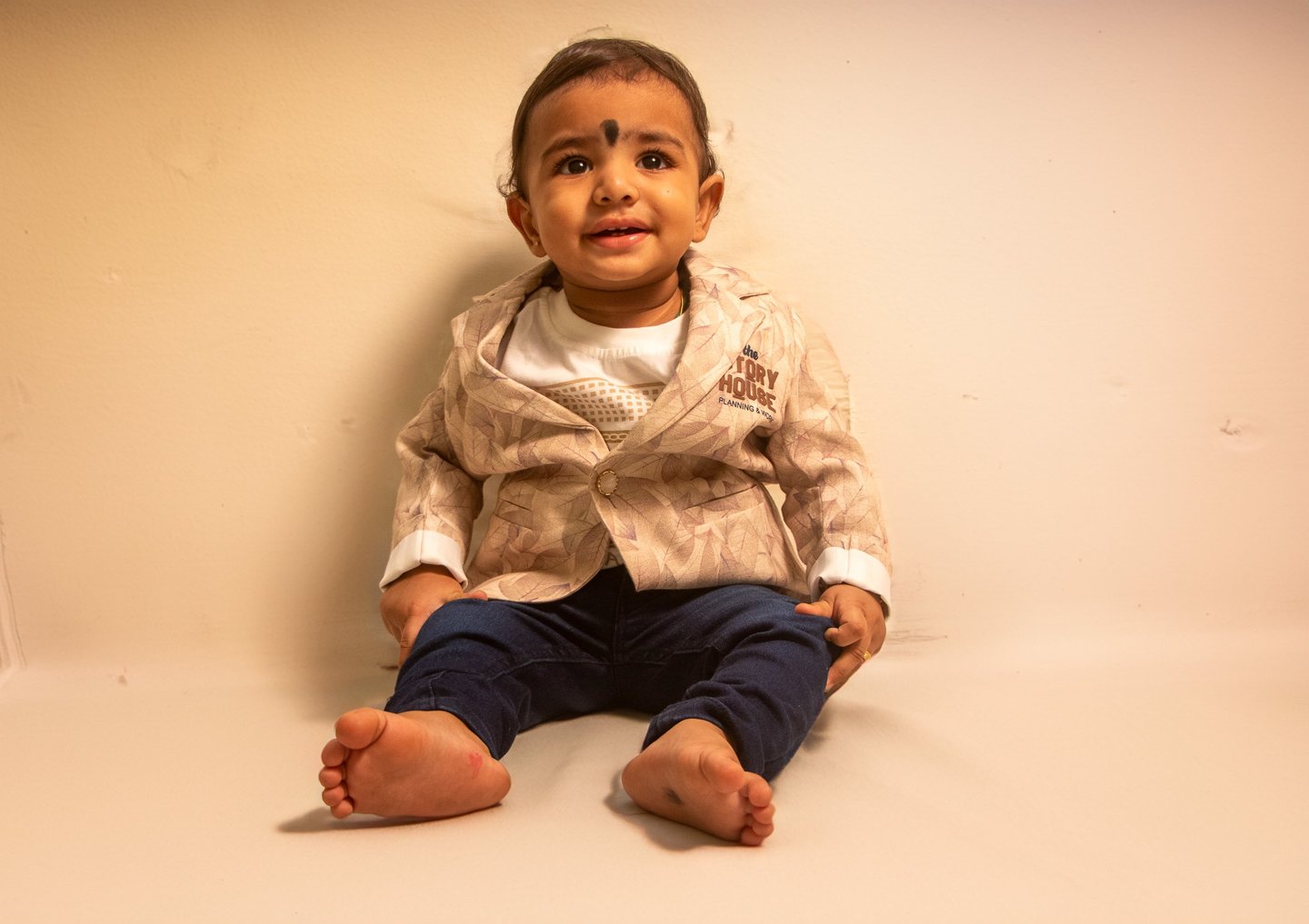 a baby sitting on a white surface with a white background