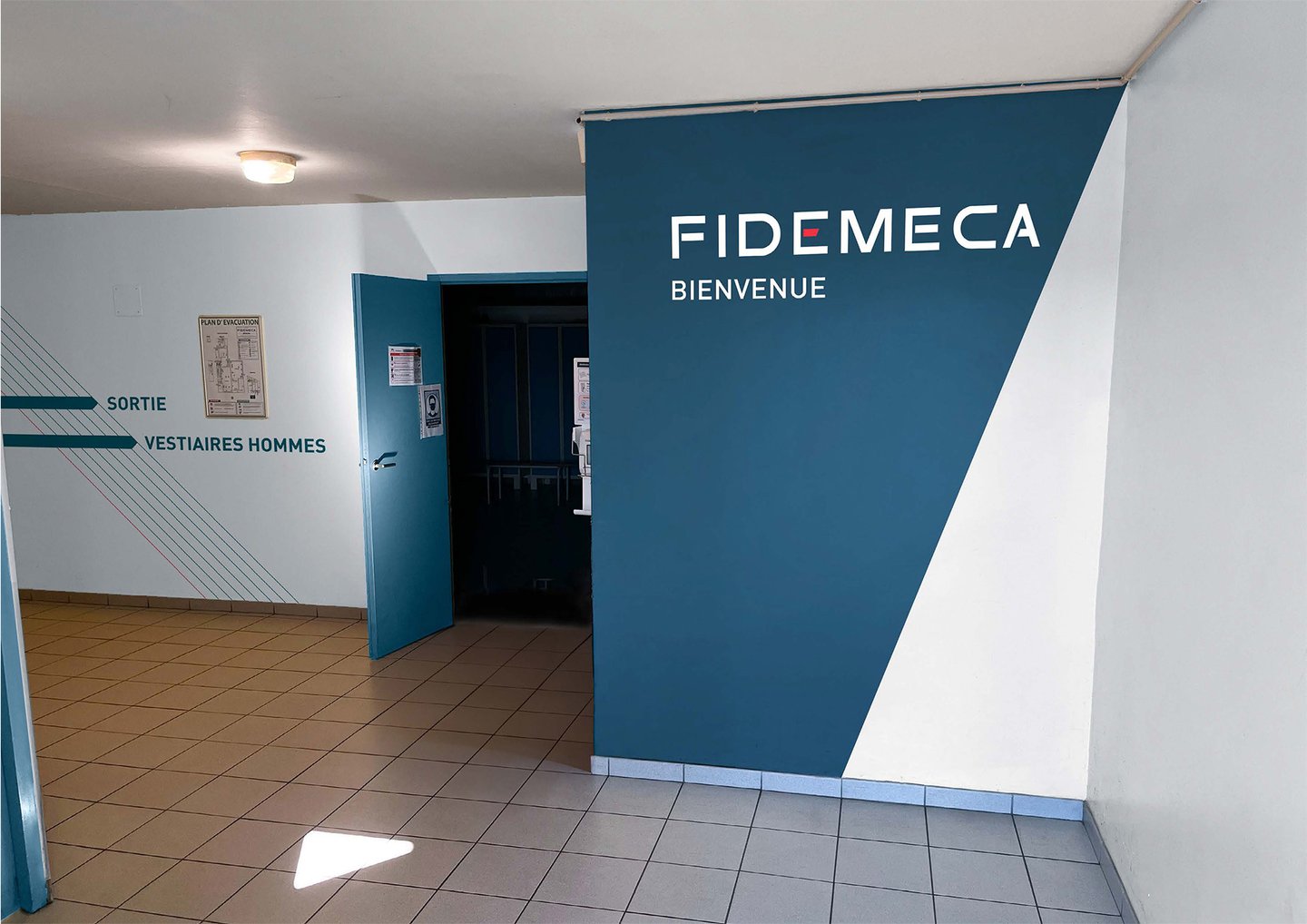 un couloir avec un panneau bleu et blanc indiquant Fidemeca