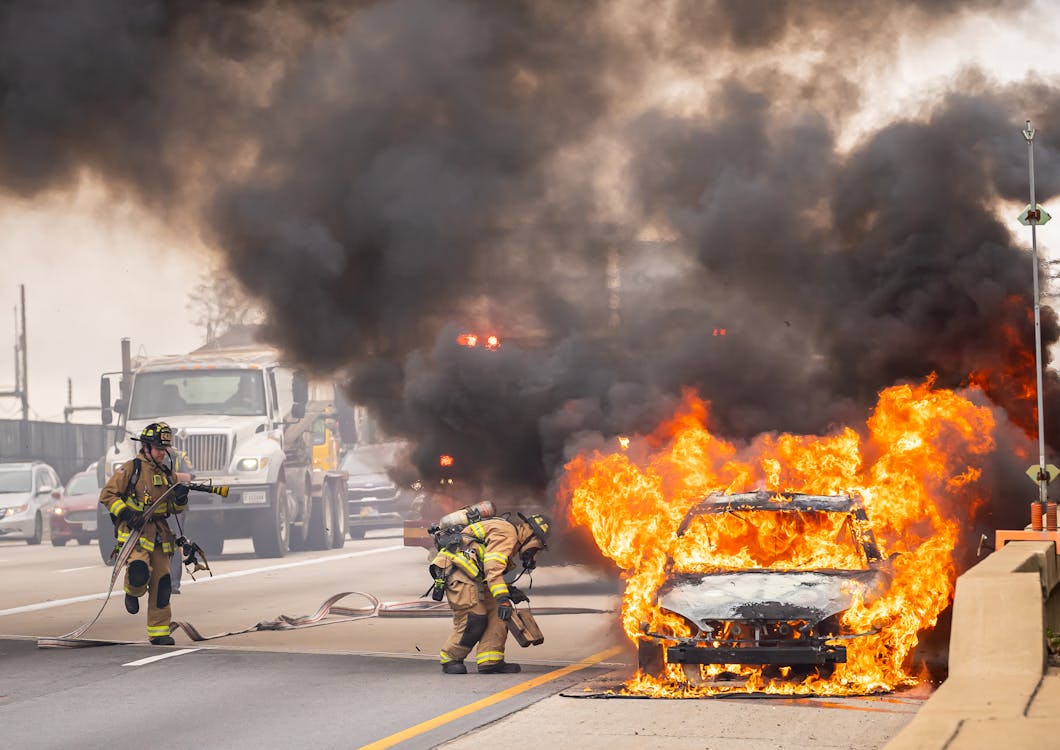 a firefighter standing in front of a car that is on fire