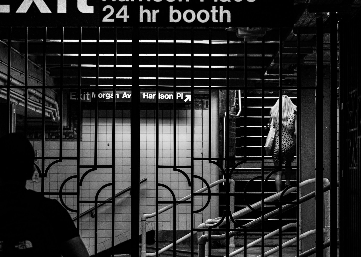 a woman walking through a subway station with bars in the foreground