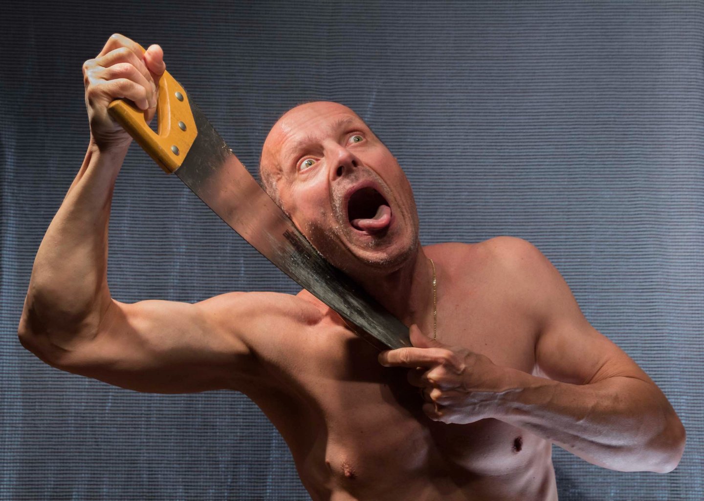 Male figure with an open mouth and a tongue out holding a handsaw blade against his neck. 