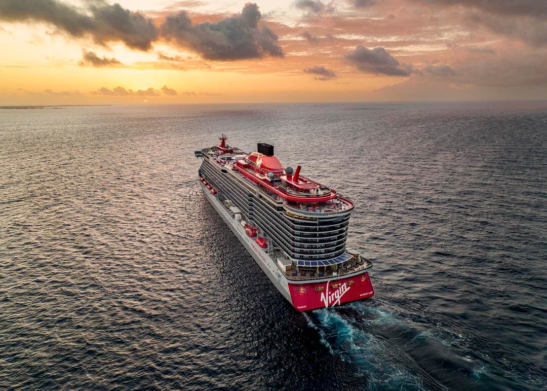 Virgin Voyages cruise ship sailing on the ocean into the sunset