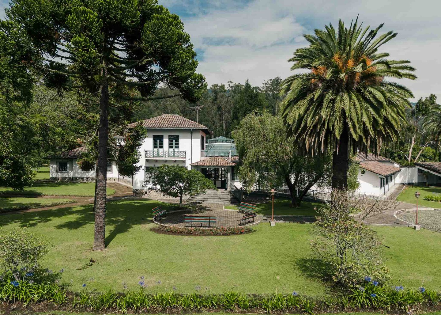 Fotografía con dron de mansión colonial de paredes blancas con techo naranja, cúpulas rodeada de naturaleza Quito Ecuador