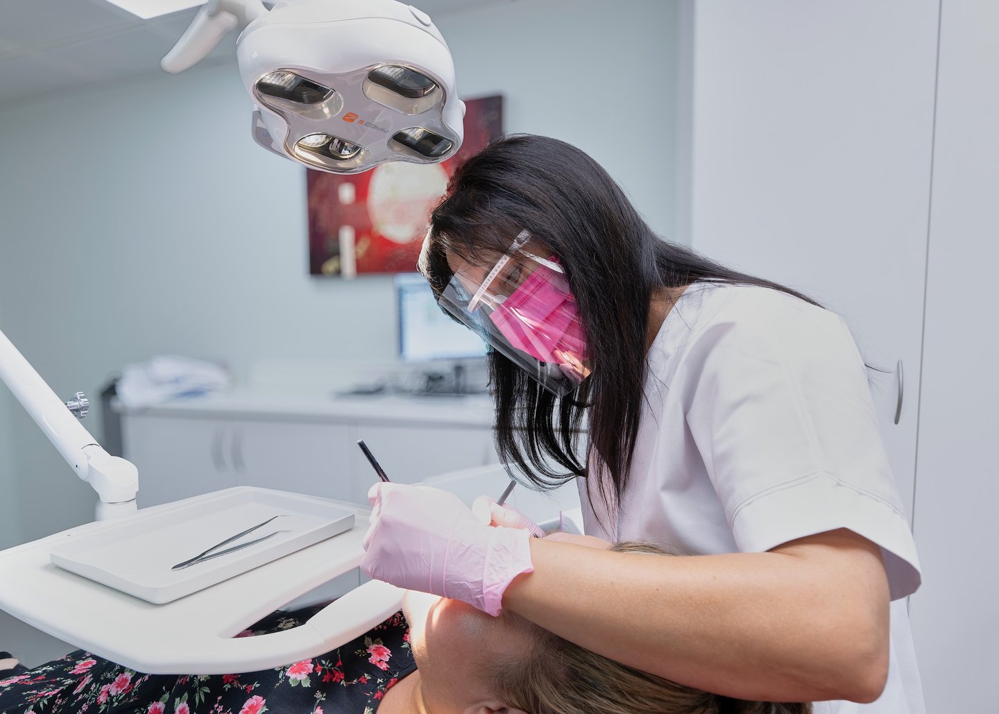 Un dentiste portant une visière de protection réalise un soin dentaire