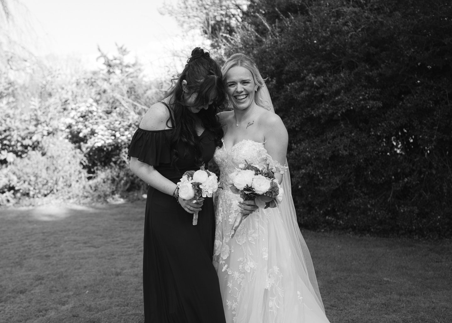Bride and bridesmaid laughing while holding bouquets at Fredricks Hotel & Spa, Berkshire