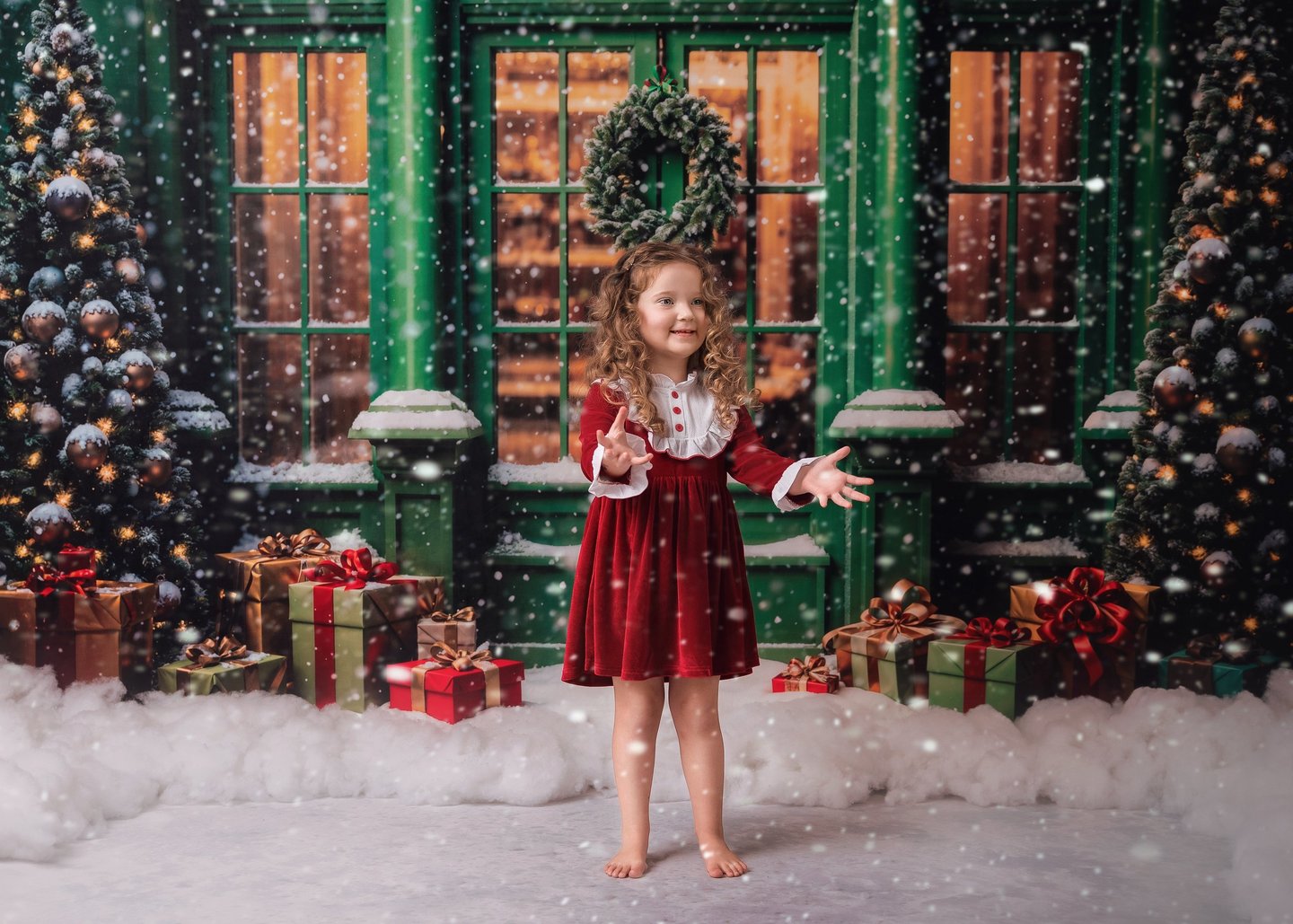a little girl in a red dress standing in front of a christmas tree