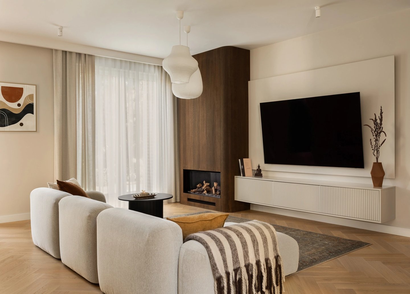 Salon Japandi: beżowa sofa modułowa, ściana TV i drewniany kominek.