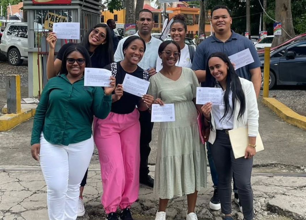 a group of people standing around a group of people holding up papers