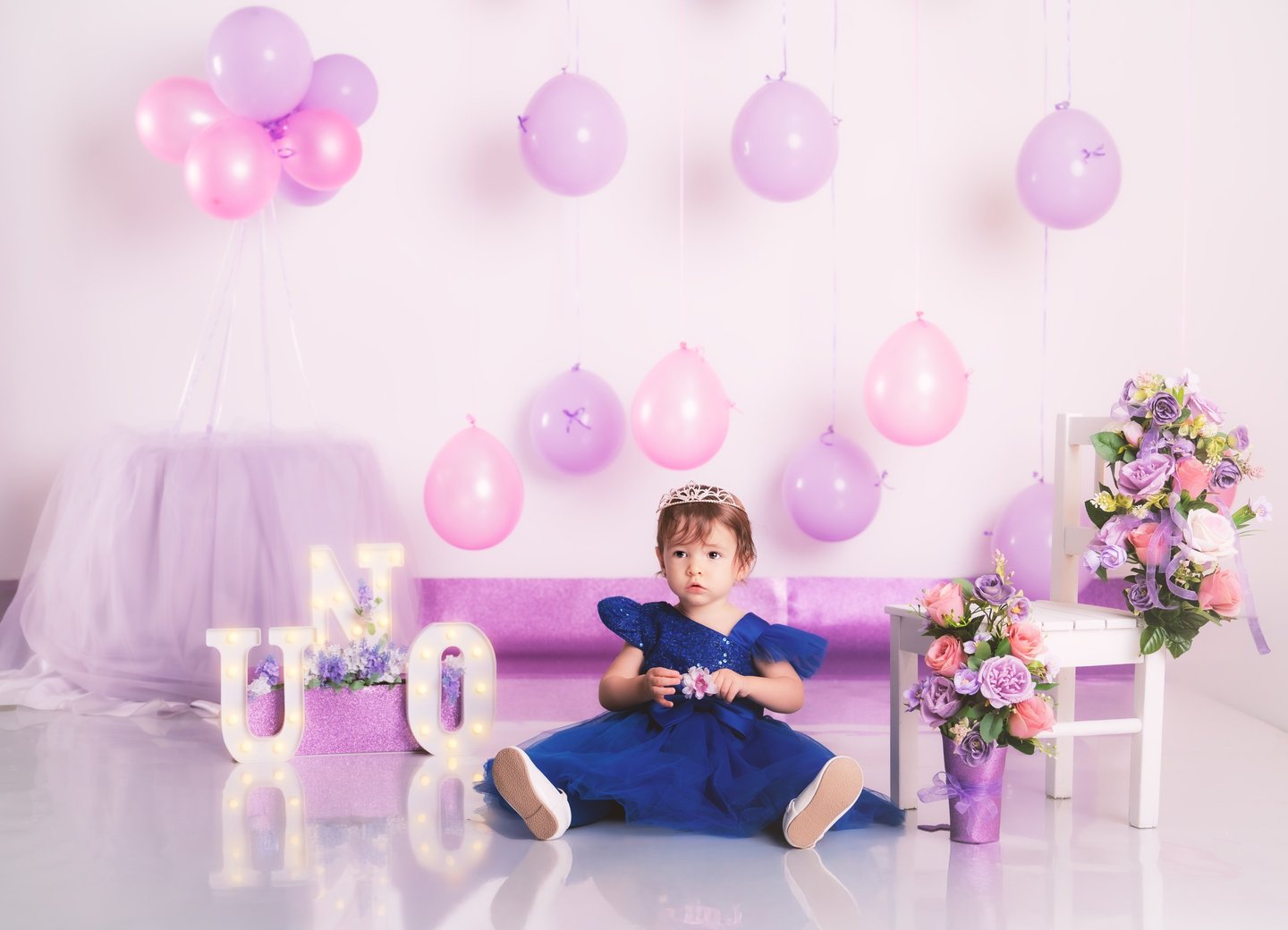 a little girl in a purple dress sitting on a couch