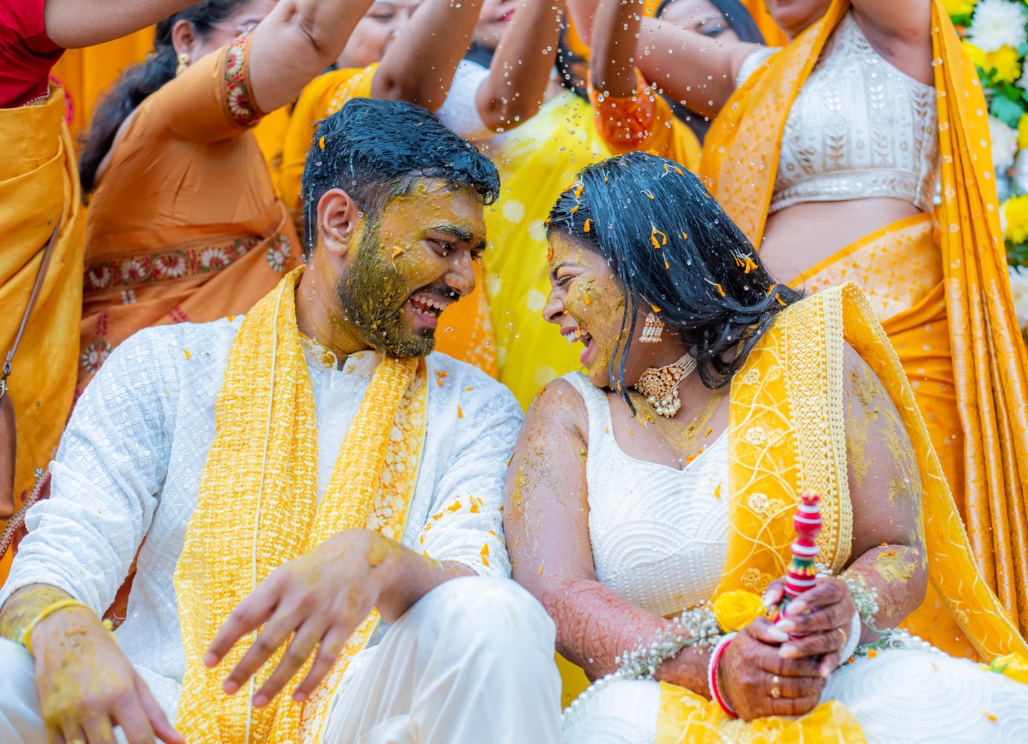 Bride and groom with yellow turmeric, smiling.