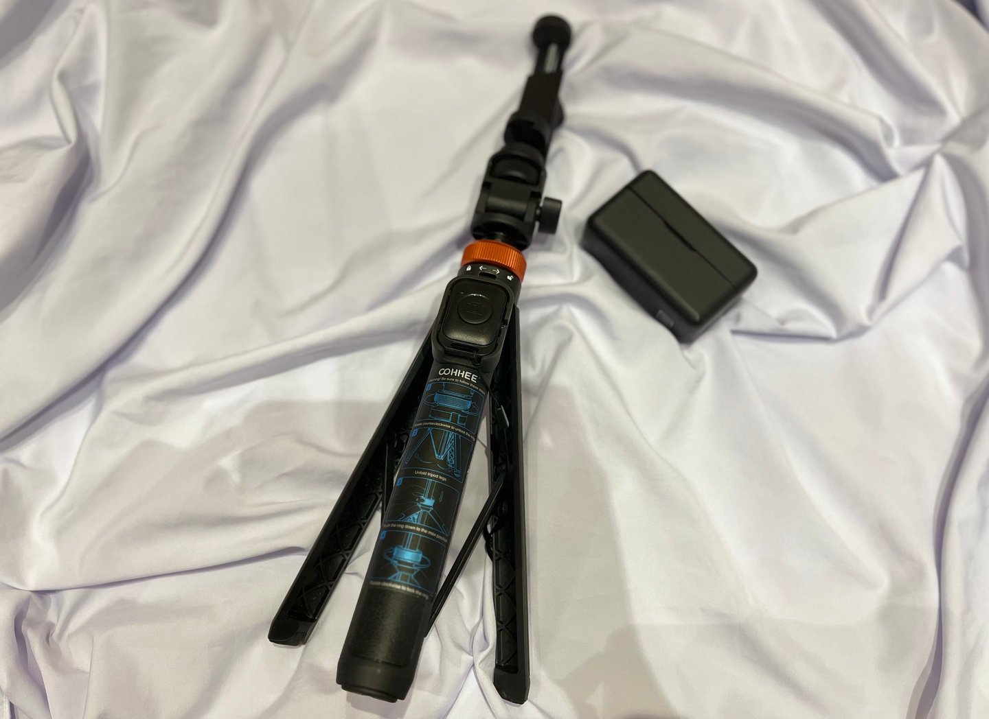Black Cohhee tripod with a microphone beside it.
