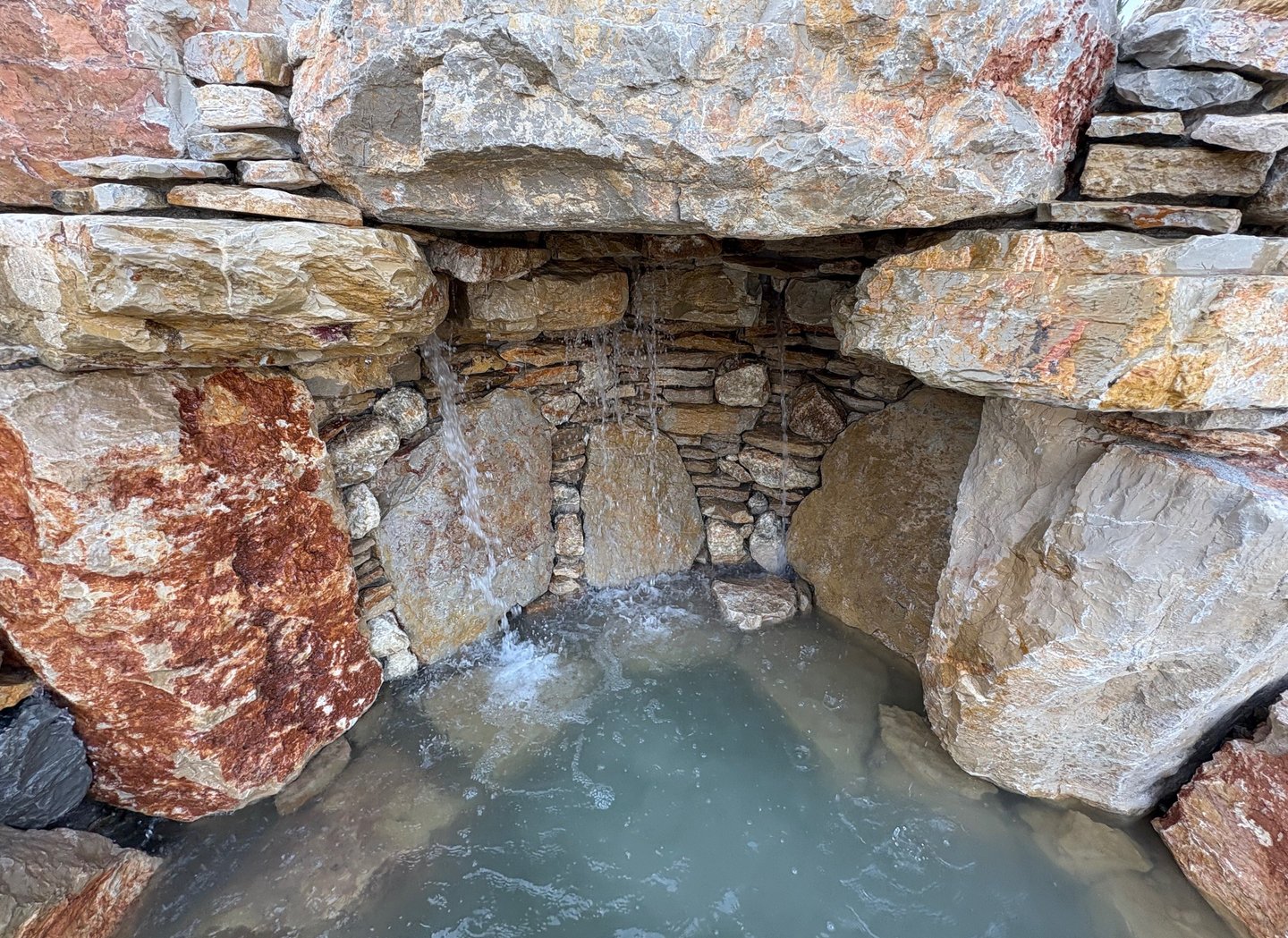 Handcrafted grotto cave under waterfall with limestone & quartzite for natural pool | Aqua Vitae