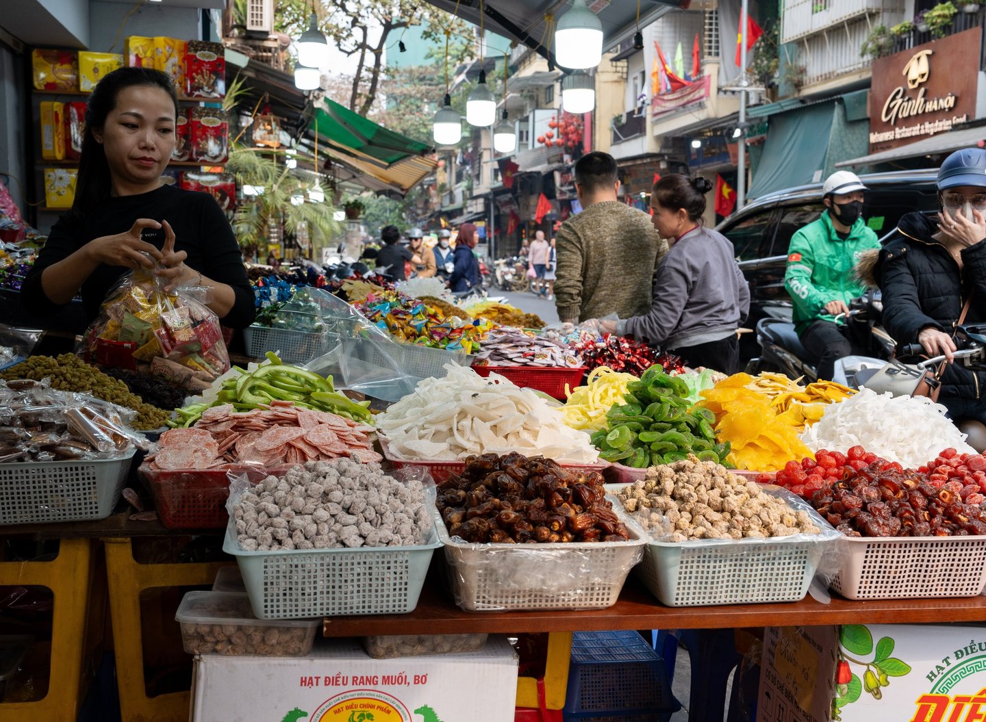 A Vietnamese woman working as a saleswoman together with a customer on his motorcycle at a street sh