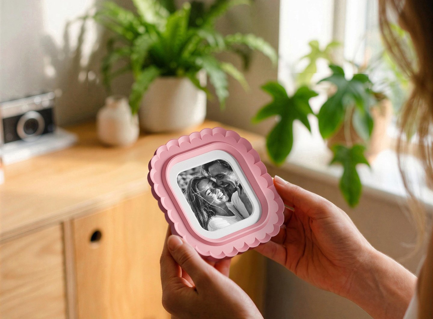 Woman holding a 3D printed photo frame in a cozy home interior with plants