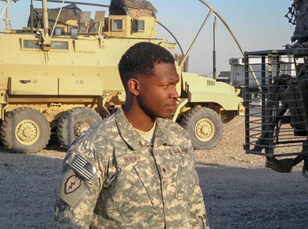a soldier in uniform standing in front of a military vehicle