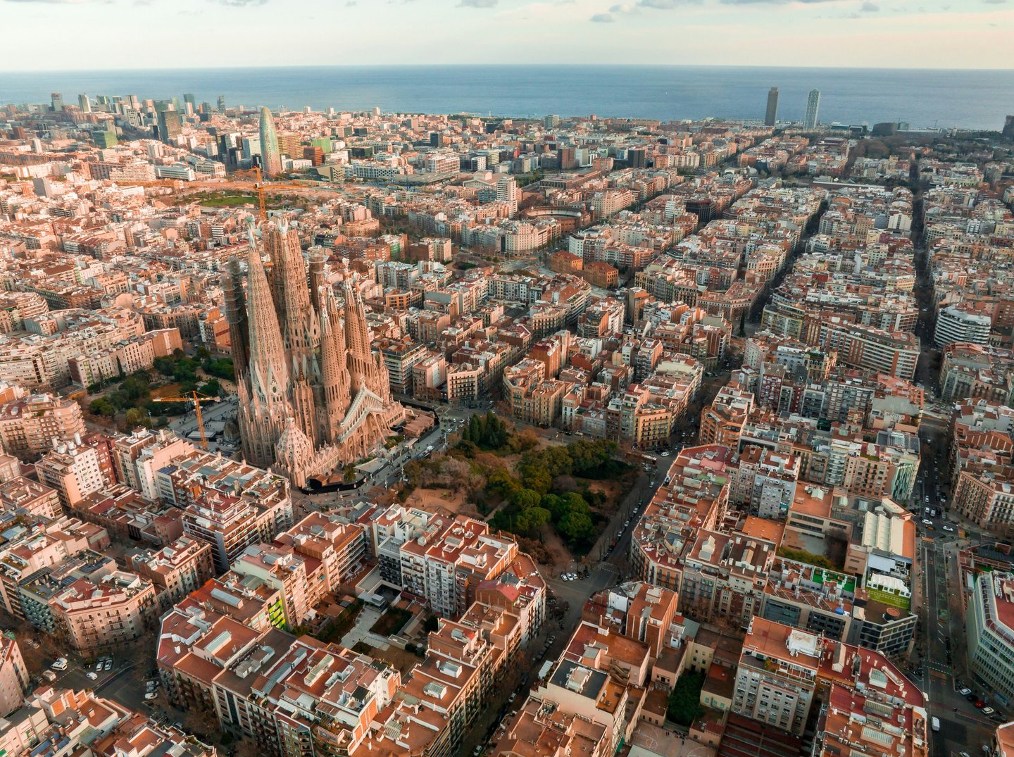 Aerial view of the Sagrada Familia and Barcelona city skyline overlooking the Mediterranean Sea.