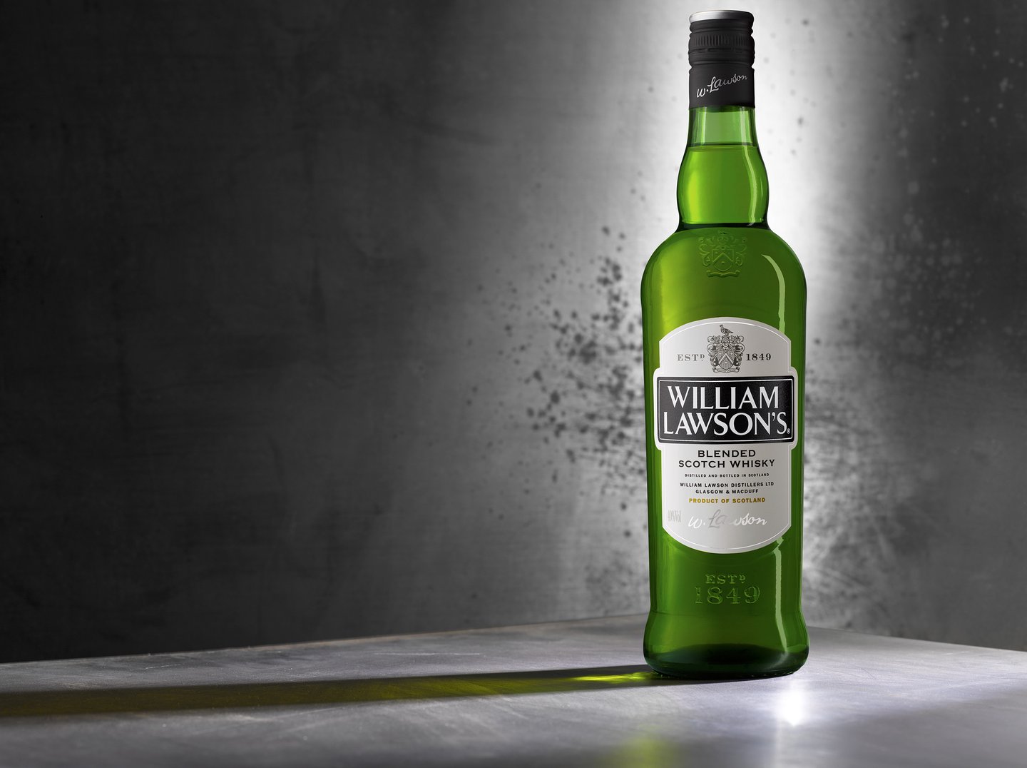 Green William Lawson's Whisky bottle on a metal background with long shadow