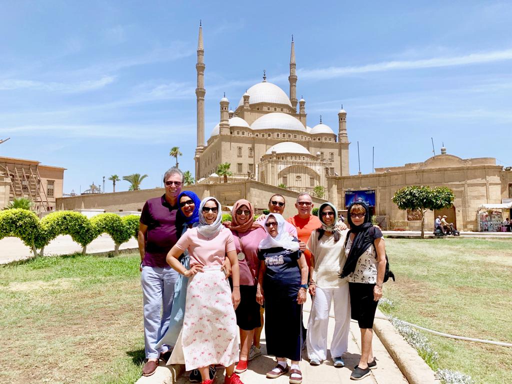 un grupo de turistas de pie frente a una mezquita de mohamed ali el cairo islámico