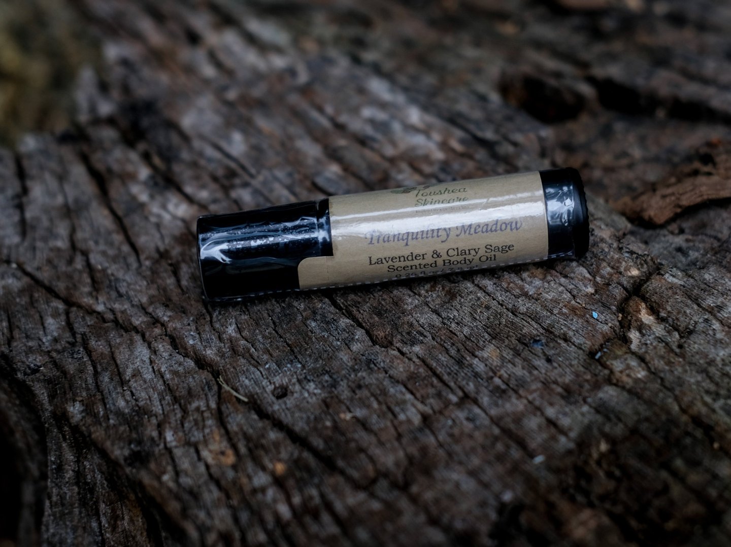 body oil in black vial on a tree stump