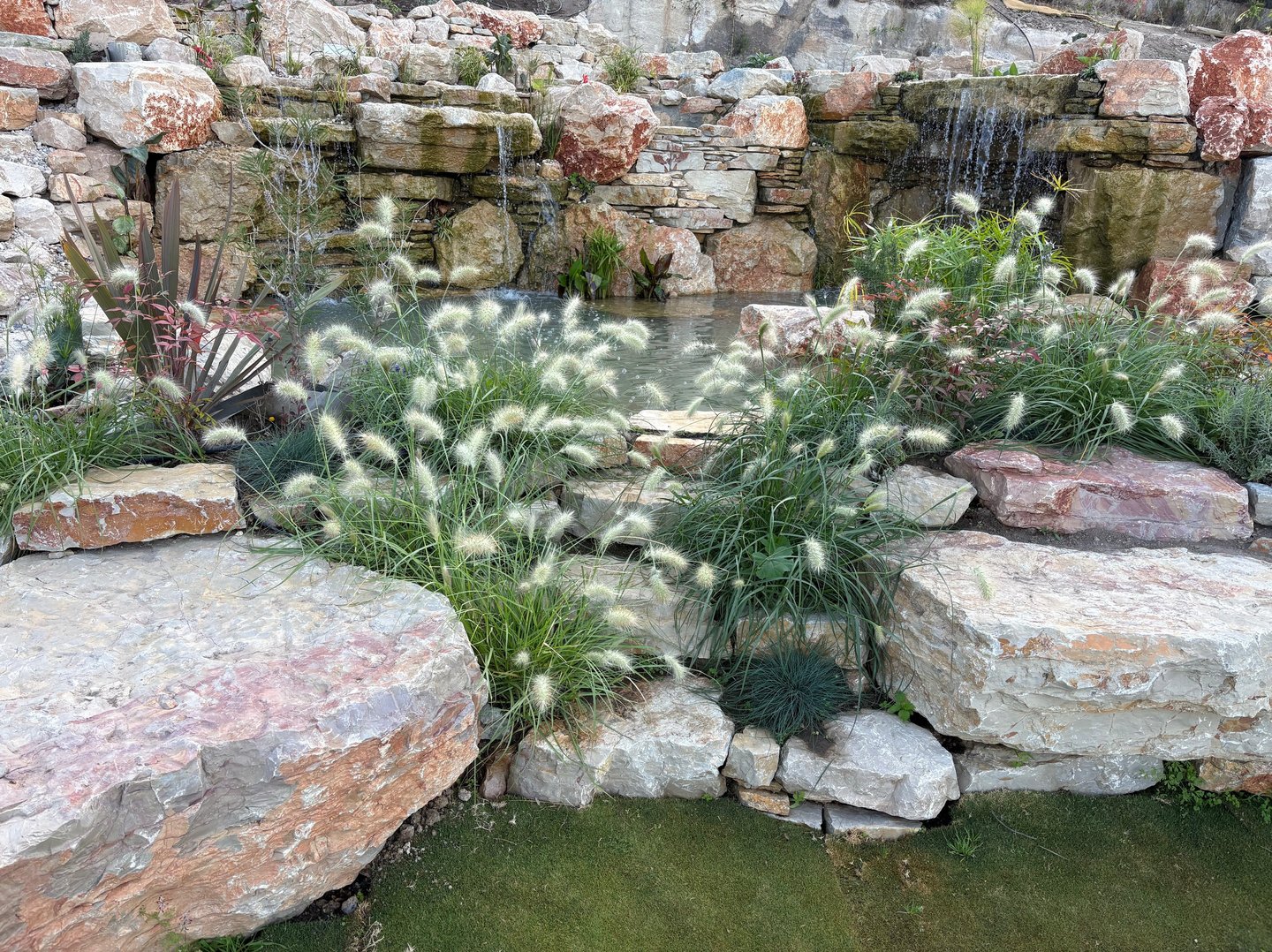 Natural pool wonderland with waterfalls, cave, stone benches & whimsical plantings | Aqua Vitae