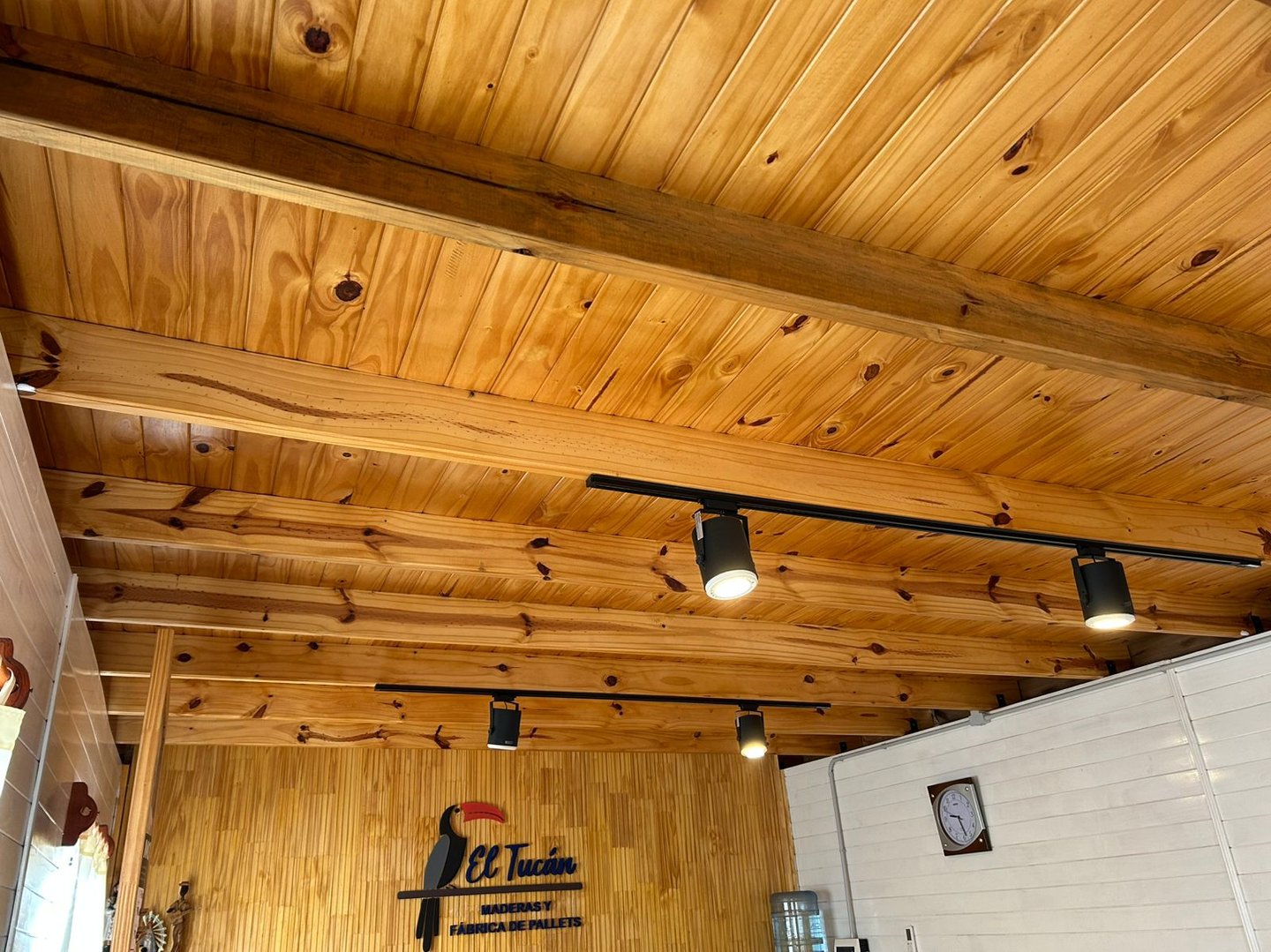 Interior rústico con techo de vigas de madera a la vista e iluminación moderna.