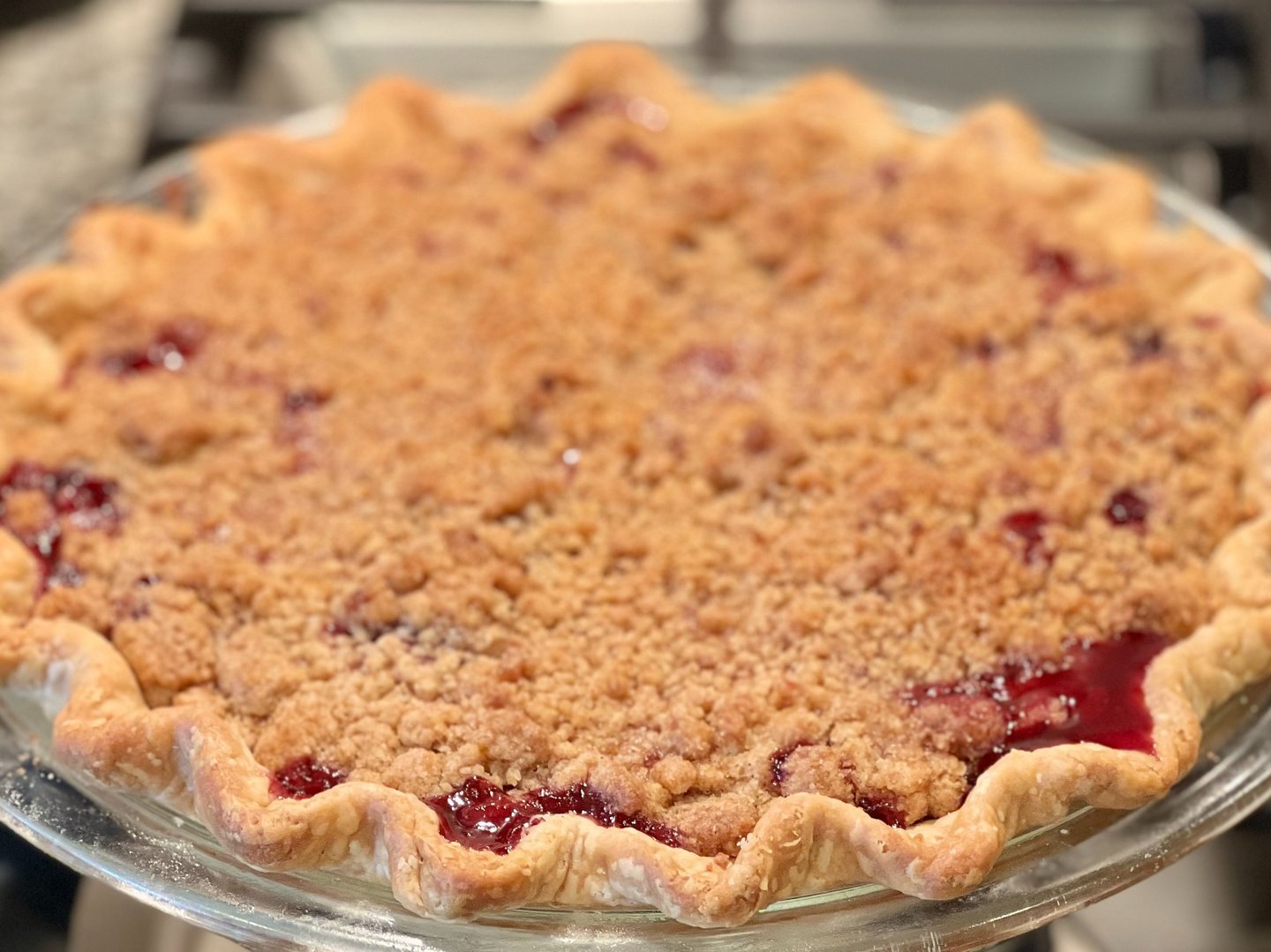 Freshly baked cherry crumble pie with a fluted golden crust and sweet streusel topping in a glass dish.