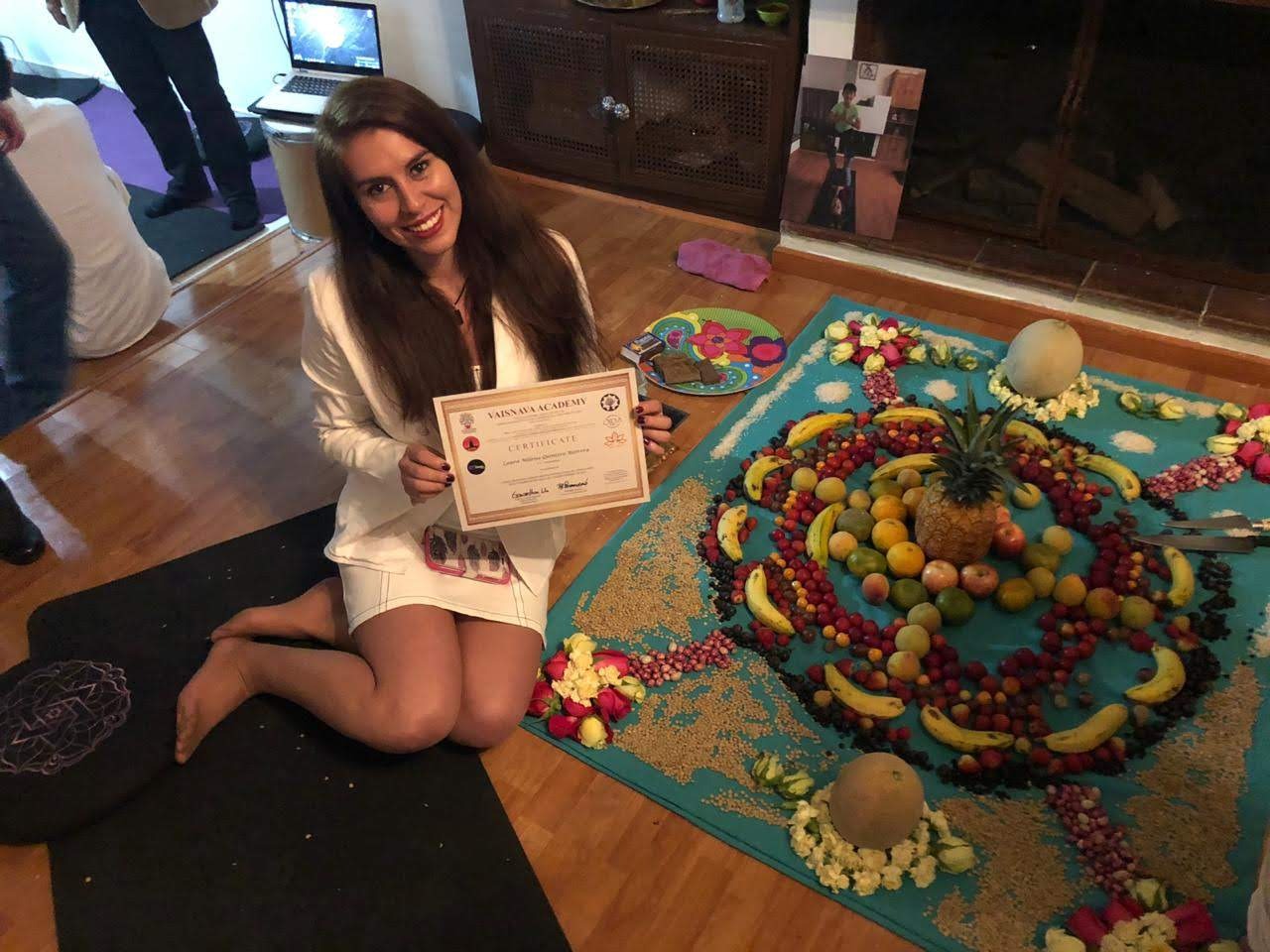 mujer sentada al lado de un mandala de frutas