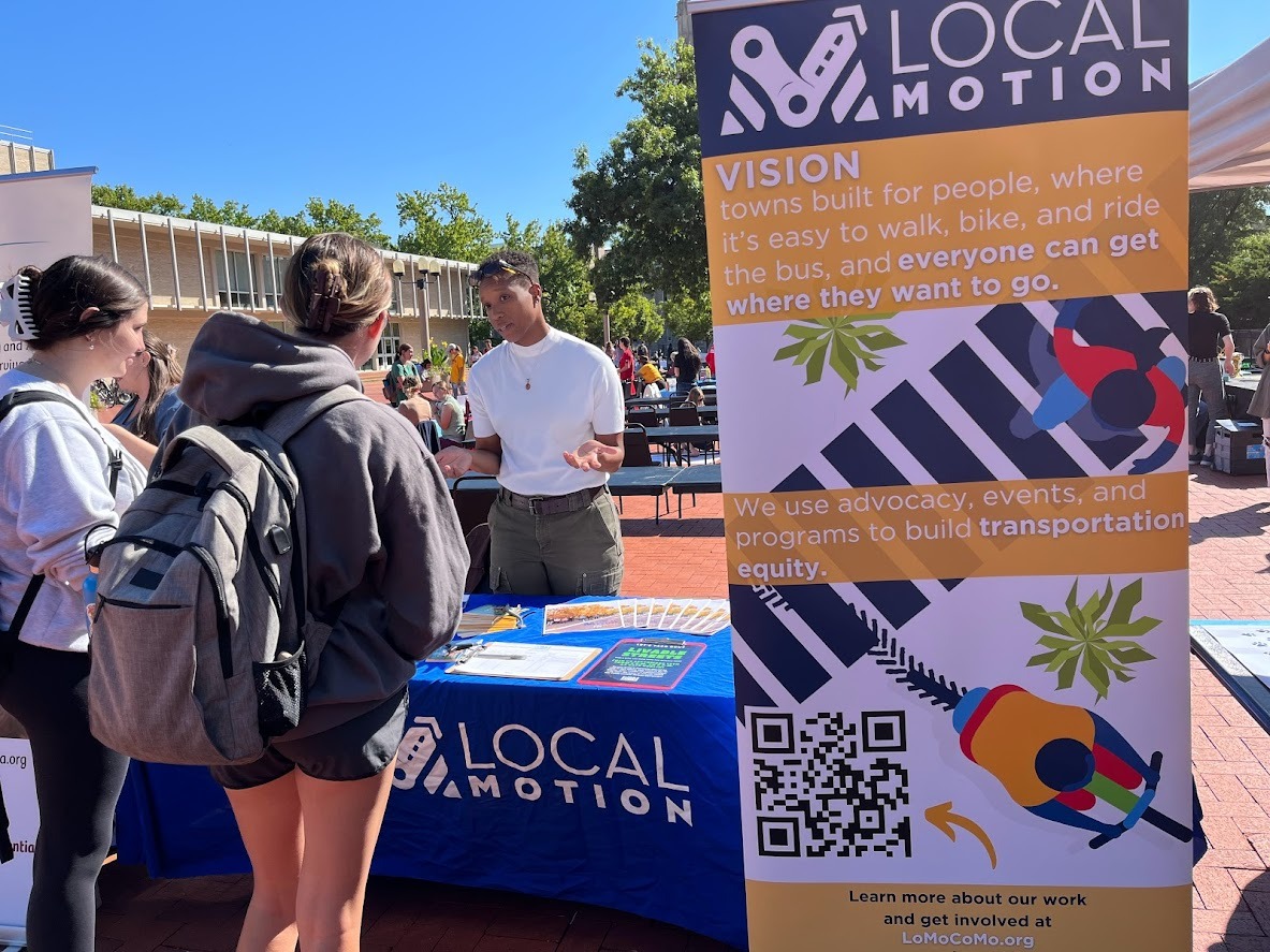 Local Motion table with a staff member talking to the public