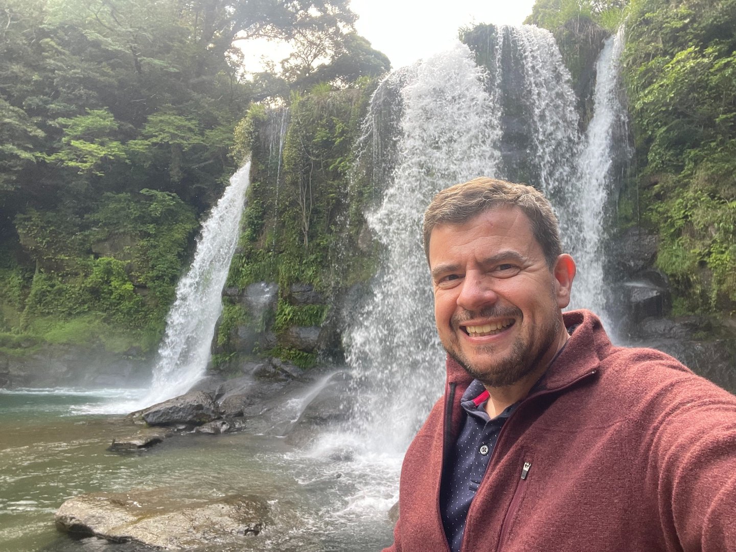 Picture of the site owner standing in front of a waterfall in Japan