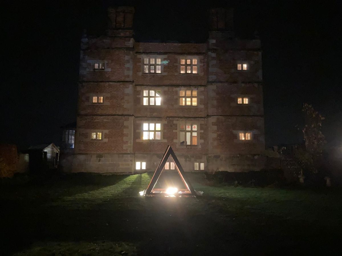 Soulton Hall seen at night with a large, steel pyramid in front