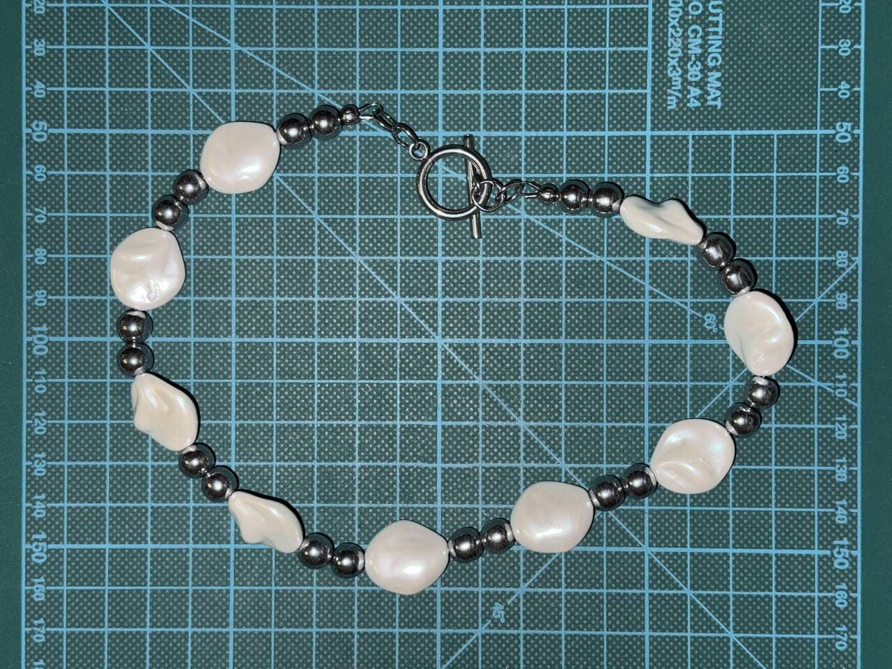 Unisex necklace with irregular pearl masses and polished hematite beads, styled with a toggle clasp