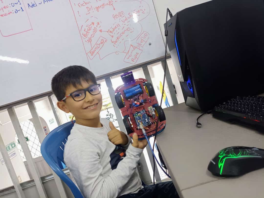 a boy sitting at a desk with a computer mouse