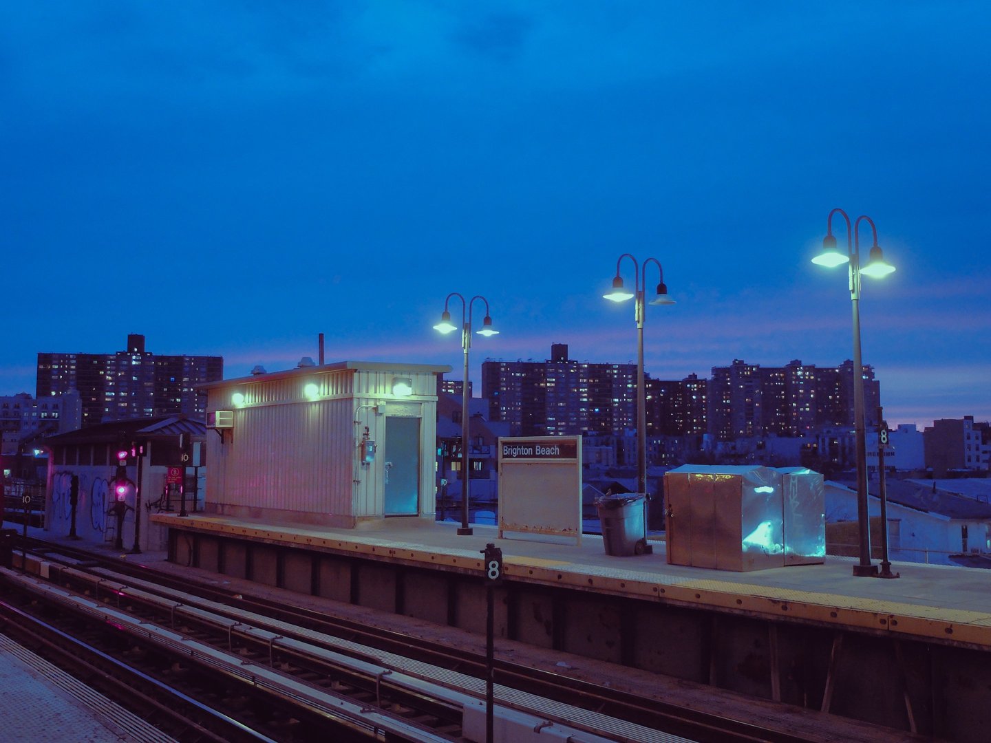 A blue hour shot of a train station, lanterns softly lighting the scene.
